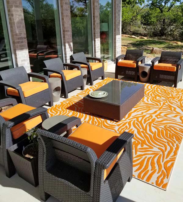 Abundance of Canvas Tangerine Seat Cushions Pop on Luxurious Patio